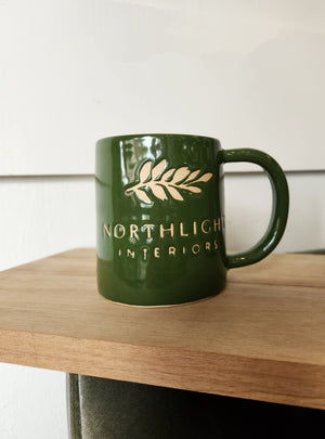 Green mug with Northlight Interior mug on a wood board.