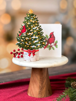 Miniature Christmas tree with a cardinal in the branches in a birch stump pop card on a pedestal.