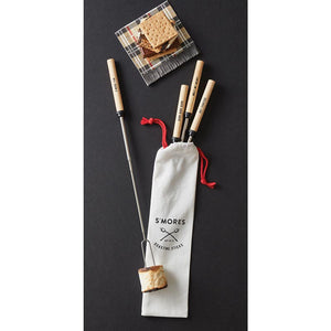 Muslin bag with set of four wood stainless steel smores sticks. Displayed on backdrop with prepared smore. 