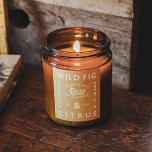 Wild fig and citrus amber glass candle with flame. 