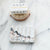 carved black and grey melange marble soap dish with bar soap and brush displayed on counter. 