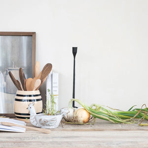 Vintage inspired black and cream striped crock vase displayed on counter with wooden kitchen utensils stored inside. 