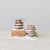 Two glass cake ornaments on fake snow, one with a gingerbread house on a wood block, and one with greenery on a pedestal.