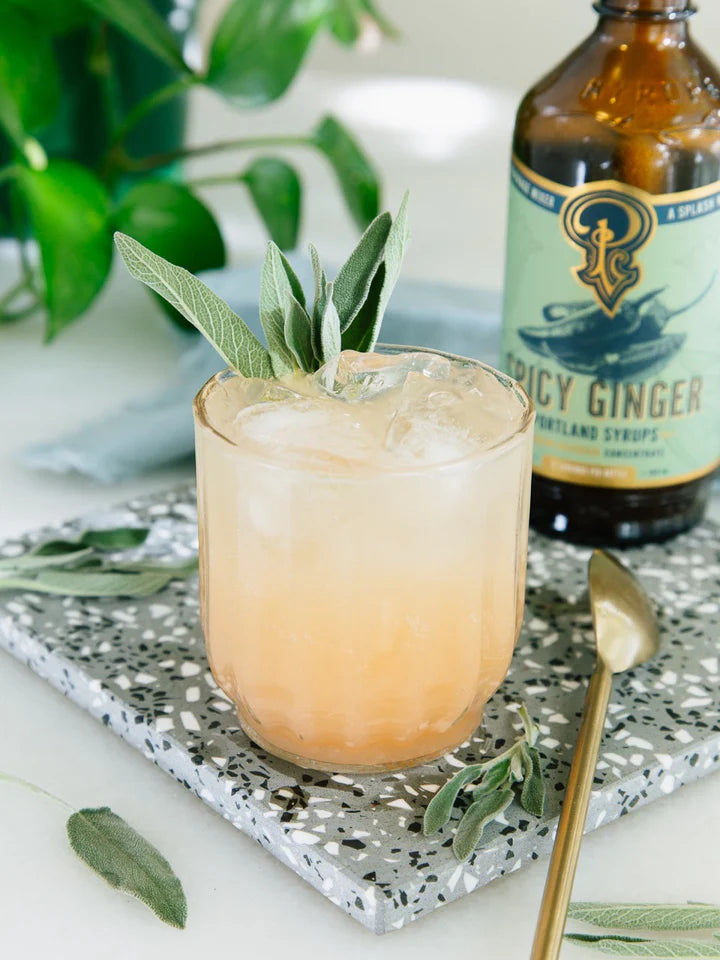 Iced cocktail with the spicy ginger syrup bottle on the tray.