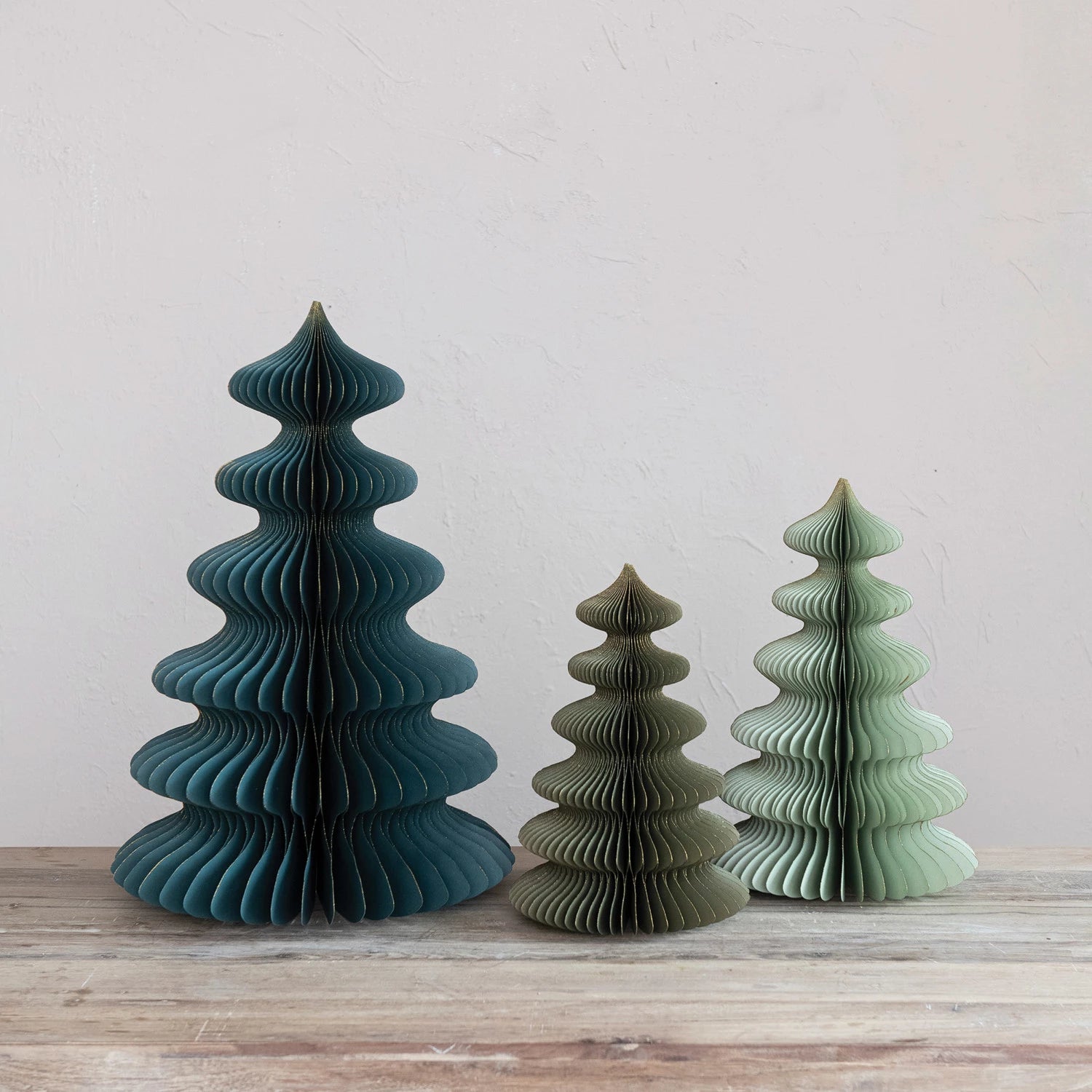 Teal, dark green, and mint colored honeycomb paper trees in varying heights. 