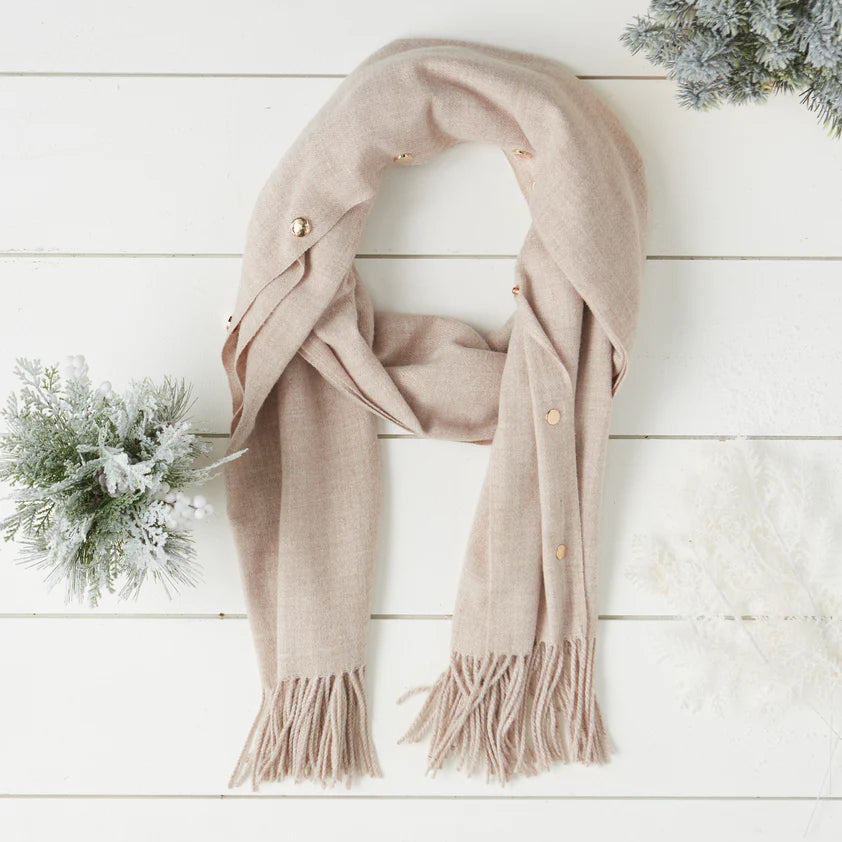 Oatmeal scarf with gold snap buttons displayed on white wood table.