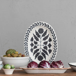 Oval stoneware hand painted black and white floral platter displayed standing up. 