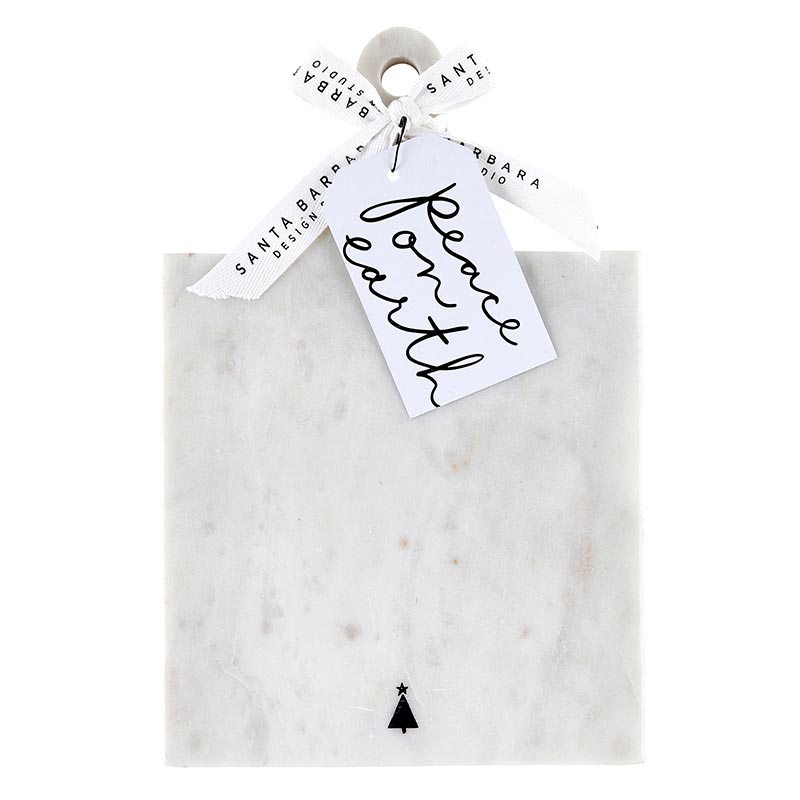 White marble serving board with small black tree on the bottom and a tag saying "Peace on Earth" in script.