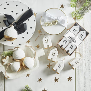 various white, black, and gold paper mache holiday ornaments displayed on table. 