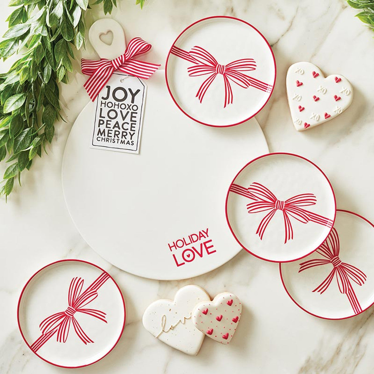 Holiday ceramic red bow appetizer plates displayed on marble white charcuterie board. 