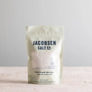 Bag of Jacobsen pure flake sea salt on white stone counter.