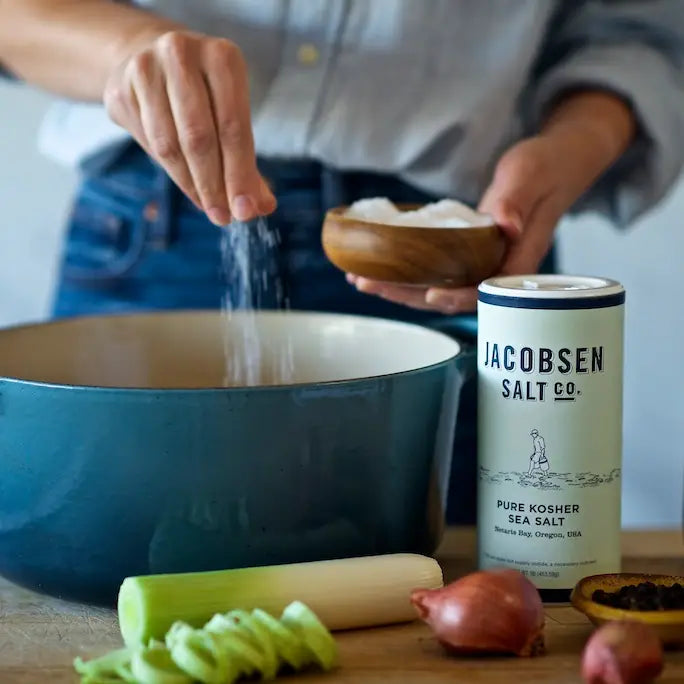 Person using Jacobsen fine sea salt in a bowl with the cannister next to her.