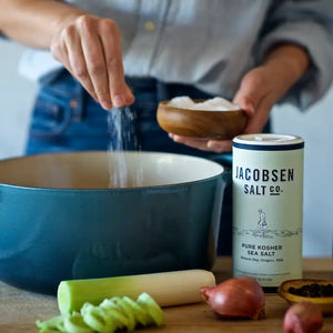 Person using Jacobsen fine sea salt in a bowl with the cannister next to her.