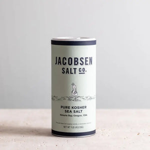 Cannister of Jacobsen pure fine sea salt on white stone counter.