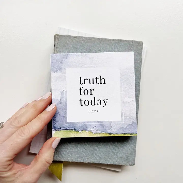 Hand holding truth for today card set on top of journals