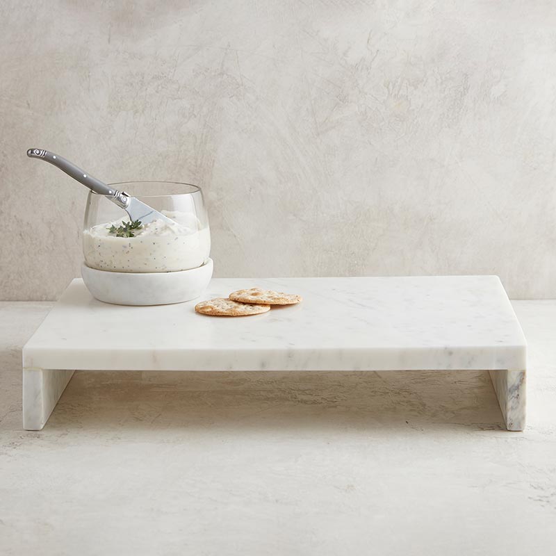 Marble waterfall pedestal with a glass vessel with soft cheese and crackers.